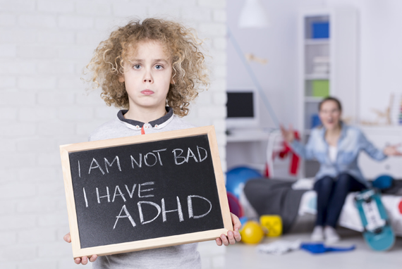 Attention-Deficit / Hyperactivity Disorder - Sad child with woman exasperated in the background. Child is holding a chalkboard sign that says, 