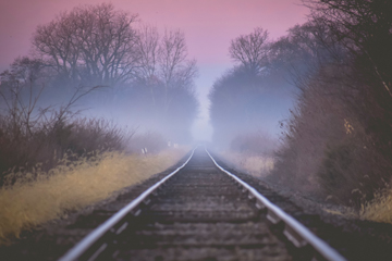 Journey of Healing - Railroad tracks going to horizon through countryside during pastel pink dawn hues